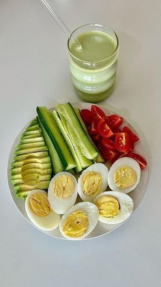 a plate with eggs, tomatoes, cucumbers and avocado on it