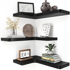 two black shelves with books and vases on top of each shelf in the corner