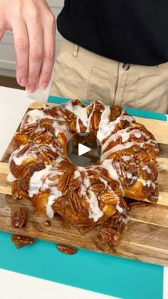 a person standing over a wooden cutting board with a bundt cake on it