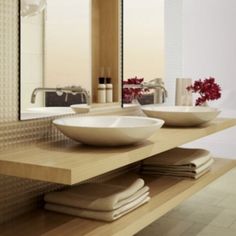 two white bowls are sitting on a counter in front of a large mirror and sink