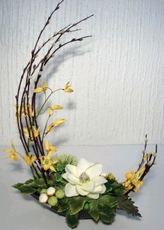 a white flower arrangement with yellow flowers and green leaves