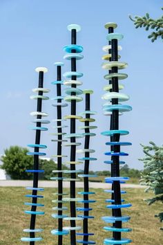 an outdoor sculpture made out of glass and black poles with blue, white and green circles hanging from them