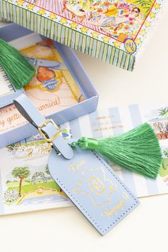 a blue box with a green tassel hanging from it's side next to a tag