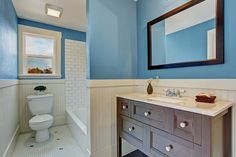 a bathroom with blue walls and white tile on the floor, along with a wooden vanity