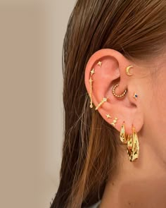 a woman wearing gold ear cuffs with stars and moon designs on the end of her ears