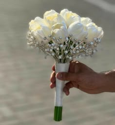 a hand holding a bouquet of white roses