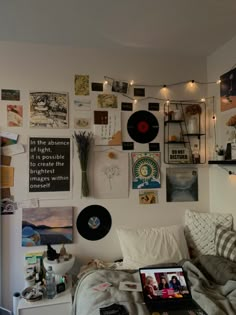 a bed with lots of pictures on the wall above it and a laptop computer sitting on top