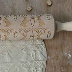 a rolling pin on top of a wooden table next to a roll of waxing paper