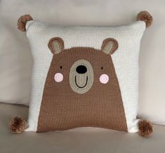 a brown bear pillow sitting on top of a white couch