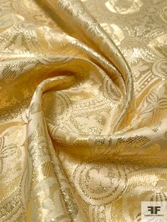 a gold and white fabric with an intricate design on it's side, as well as