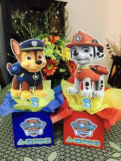 three paper bags with paw patrol characters on them sitting on a table next to a bouquet of flowers