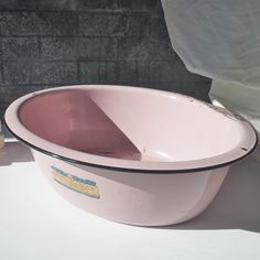 a large pink bowl sitting on top of a white table next to a brick wall