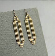 These great earrings are made with solid brass and feature a graduated art deco design.  They remind us of classic Deco architecture, like the Chrysler building!   The earrings measure 45mm (just under two inches) in length and have gold plated ear wires.   They have been designed and made in our Edinburgh studio.   This piece of handmade jewellery comes packaged in a nice recycled gift box with a handmade tag, all ready to give or keep. We also have these earrings in silver, as well as  many other Art Deco designs!  🖤 FASTER SHIPPING 🖤 Need this fast? We offer a Faster Shipping option here: https://www.etsy.com/uk/listing/100107311/faster-shipping-priority-post-upgrade 🖤 GIFT MESSAGE & WRAP SERVICE! 🖤 https://www.etsy.com/uk/listing/750160511/gift-wrap-wrapping-personalised-card?ref=l Art Deco Jewelry Rings, Art Deco Inspired Jewelry, Cement Jewelry, Gold Art Deco Earrings, Art Deco Jewellery Design, Art Deco Jewellery, Bijoux Art Deco, Silk Purse, Minimalist Earrings Gold