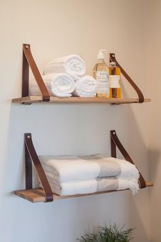 two wooden shelves with towels and soaps on them next to a potted plant