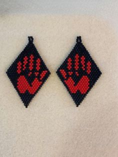 two red and black beaded earrings on a white surface with the same design as it appears