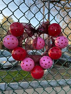 a heart shaped wreath hanging on a chain link fence