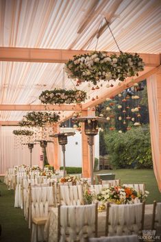 an outdoor wedding venue set up with white linens and floral arrangements hanging from the ceiling