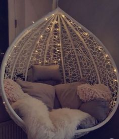 a white hanging chair with pillows and lights