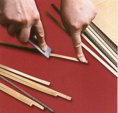 a person is cutting wood with a pair of scissors and some chopsticks on a red surface