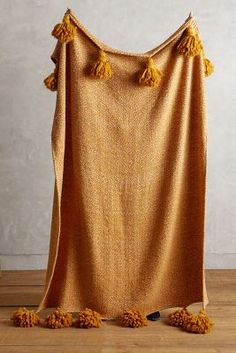 an orange blanket with tassels hanging from it's sides on a wooden floor