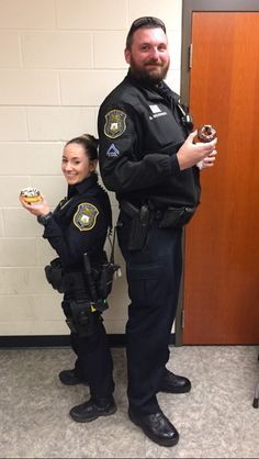 two police officers standing next to each other in front of a door holding donuts