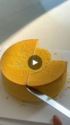 someone is cutting into a yellow cake with a knife