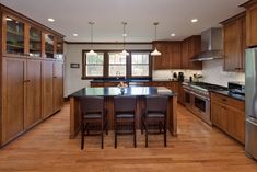 a kitchen with wooden cabinets and an island in front of a stove top oven next to a refrigerator