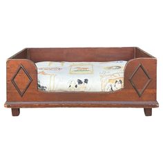 an old wooden dog bed with a pillow on it