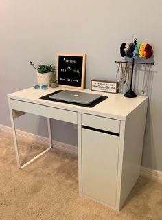 a white desk with a chalkboard on top and a laptop computer sitting on it