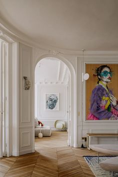 a living room with a large painting on the wall and wooden floors in front of it