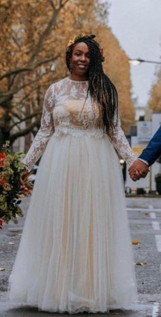 a man and woman holding hands while walking down the street