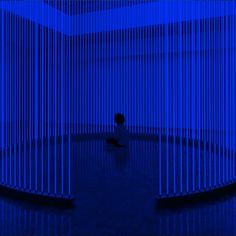 a person sitting on the floor in front of a blue wall with vertical lines covering it