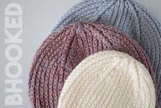 three knitted hats with the words hooked up above them in white, grey, and pink