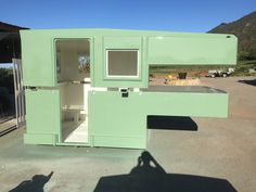 a green portable toilet sitting in the middle of a parking lot