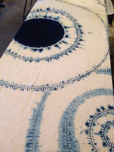 the table cloth has been dyed with blue and white dyes on it, as well as black circles