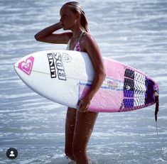 a young woman holding a surfboard in the ocean