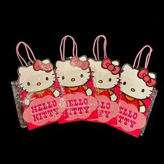 four hello kitty bags with tags attached to them on a black background and pink ribbon