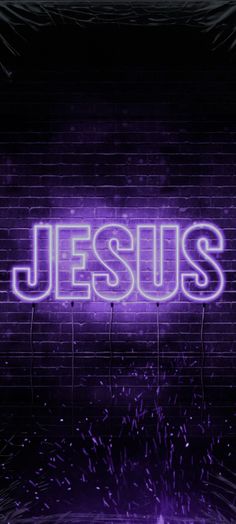 the word jesus is lit up against a brick wall