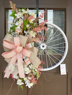 a bicycle wheel with flowers tied to it hanging from the front door and wreath on the side