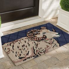 a door mat with a ram on it in front of a house and potted plants