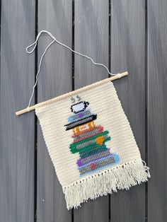 a wall hanging with a beaded snowman on it's side and a wooden stick in front of it