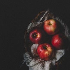 a basket filled with red apples sitting on top of a table