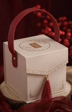 a white box with a red tassel is sitting on a table next to berries