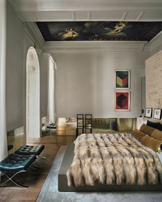 a large bed sitting in the middle of a bedroom next to a painting on the wall