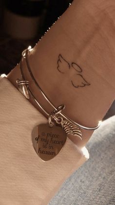 a woman's arm with a heart shaped charm on it and a small tattoo