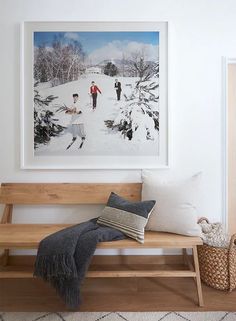 a wooden bench sitting in front of a painting on the wall next to a basket