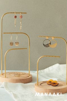 two gold jewelry stands with earrings on them