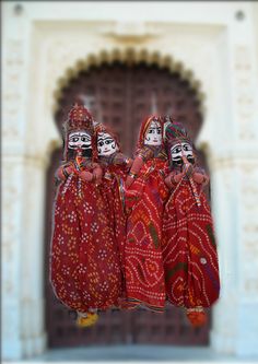 two women dressed in red and white with painted faces on their heads hanging from strings