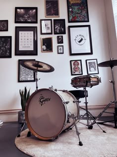 a drum set sitting on top of a rug in front of a wall covered with pictures