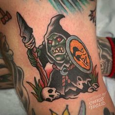 a tattoo with an image of a demon holding a knife and pumpkin on it's leg